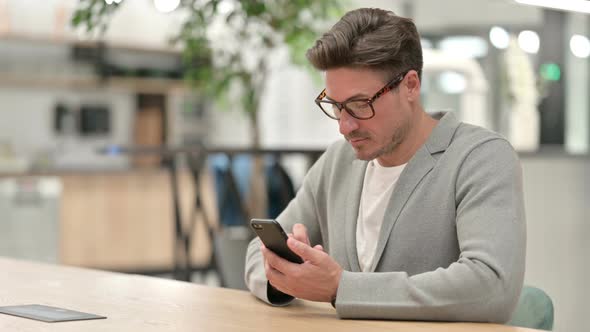 Middle Aged Man Using Smartphone in Office 