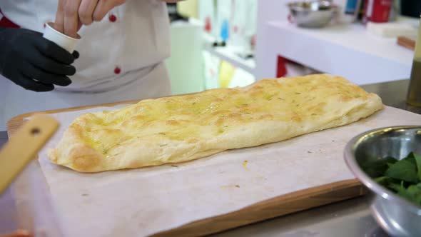 The Cook Sprinkles Spices on a Large Freshly Baked Tortilla. National Italian Cuisine