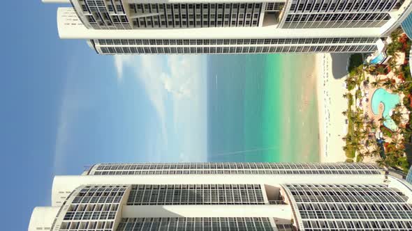 Vertical Aerial Drone Flying Between Buildings To Reveal Beach Ocean