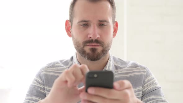 Excited Man Cheering Success on Smartphone