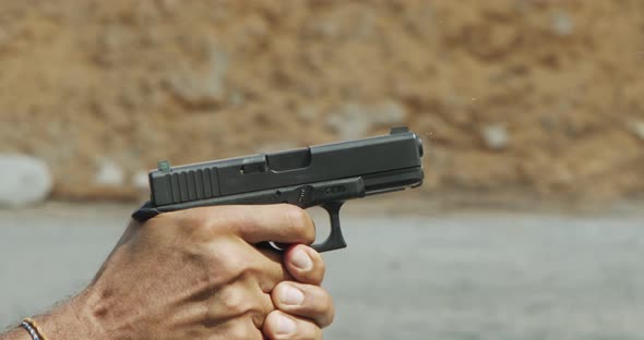 Slow motion of a hand gun firing in a firing range with cartridge flying away