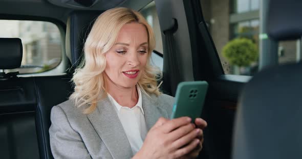 Business Woman Writing Message and Chatting on Smartphone in Modern Car.