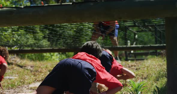 Kids crawling under the net during obstacle course training