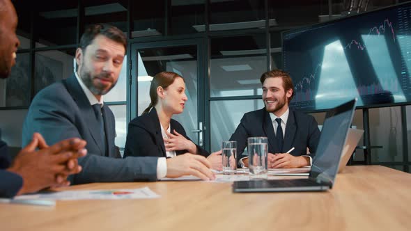 Smiling business analysts discussing a project at a meeting