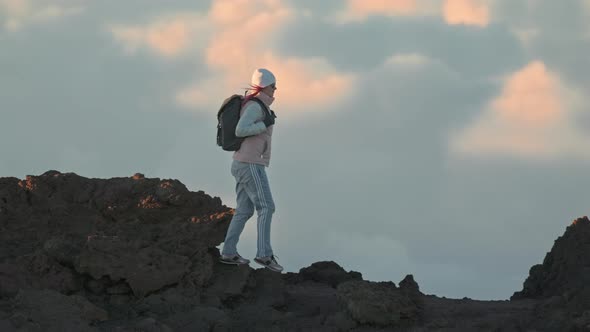 Active Woman Walking on Volcano Mountain Edge on a Sunny Cloudscape Background
