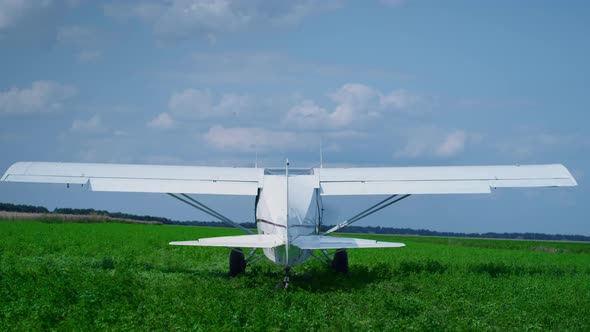 Small Airplane Starting Engine Standing on Countryside Green Field Sunny Day