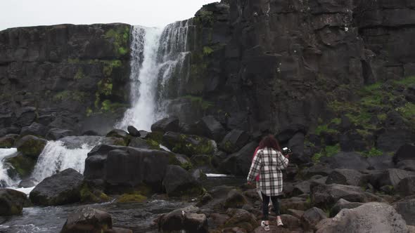 Couple Walking Towards Oxararfoss Waterfall In Thingvellir