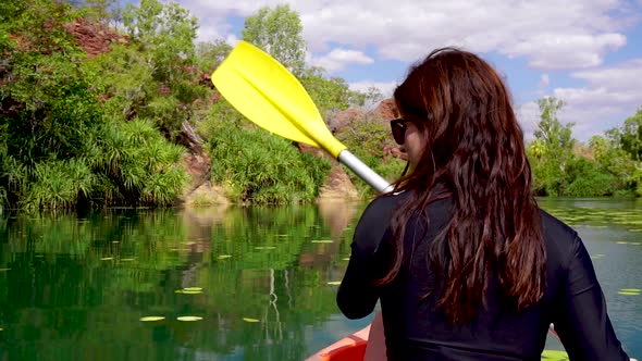 Girl canoeing down scenic river in an oasis in the Australian Outback.