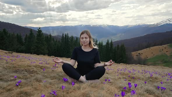 Calm Woman Meditating Sitting on Valley of High Mountain Among Crocus Flowers