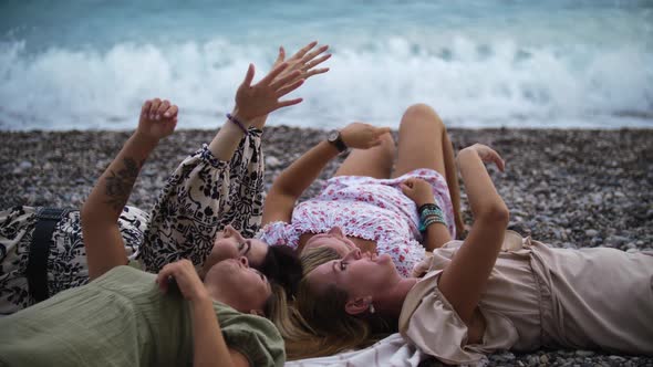 Four Women Lying on the Blanket By the Blue Sea and Looking at the Sky