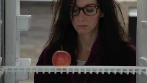 Woman Looking Annoyed at Apple in Fridge