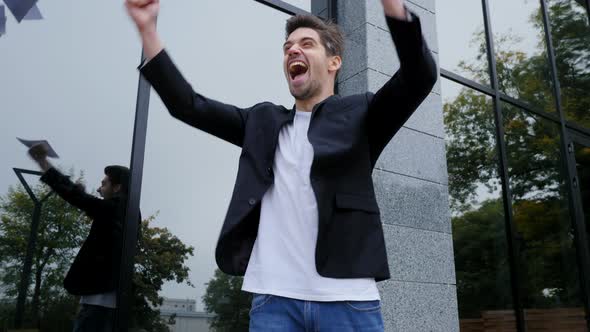 Businessman throwing papers documents into air and celebrates success on office building 