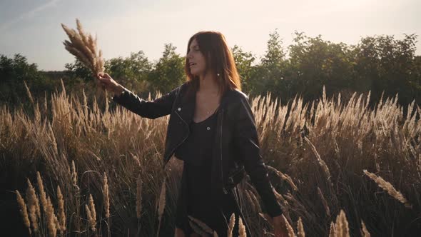 Beautiful Young Woman in the Field Spins with Flowers and Spikelets