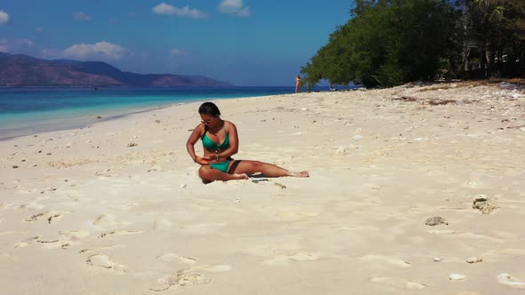 Beautiful ladies posing on tropical island beach trip by aqua blue ocean and white sandy background 