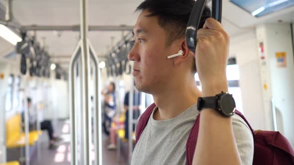 Close Up of Young Man Listening to Music with Wireless Earpods While Commuting By Train