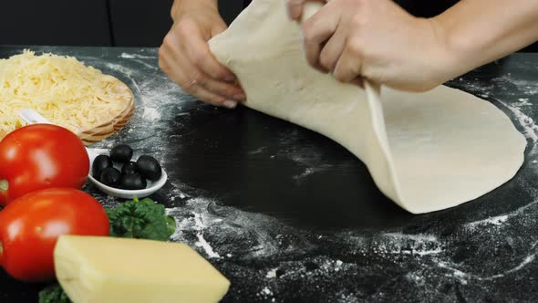 Hands are tossing pizza dough on table