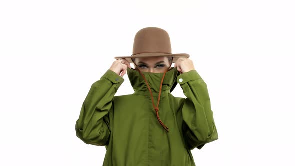 Woman in a Autumn Look in Studio in Green Parka and Hat Turns and Poses To the Camera