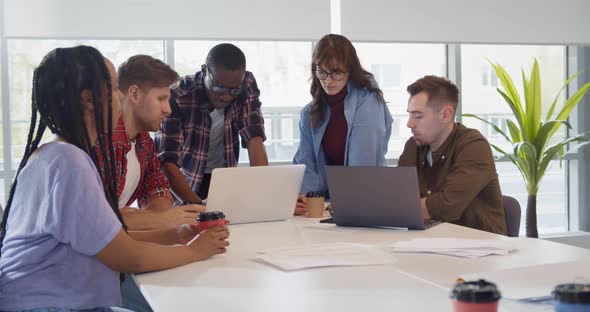 Group of Young Colleagues Using Laptop at Office Meeting