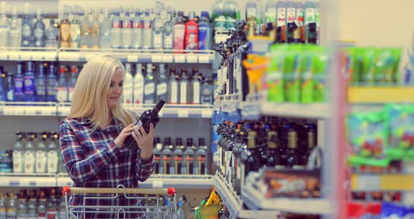 Young Beautiful Woman Chooses Wine In The Supermarket