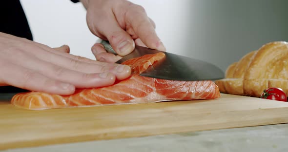 Slow Motion. Chef Begins To Cut with a Knife Fish To the Wooden Board. Close Up,