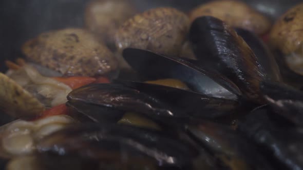 Preparing Tasty Mussels and Scallops on Pan in Burning Fire