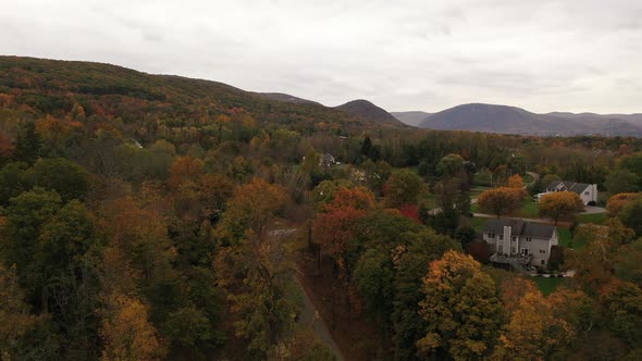 An aerial drone shot of the colorful fall foliage in upstate NY. The camera dolly in over treetops i