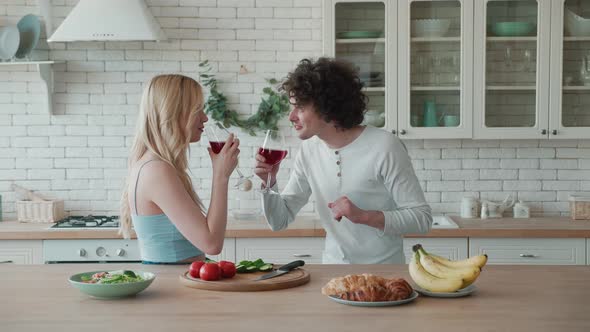Young Couple Eating Salad and Fruit Drink Red Wine in the Kitchen