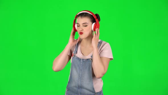 Girl Dancing and Singing in Big Red Headphones on Green Screen at Studio