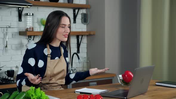 Emotional woman housewife tells chef teacher online video call laptop in kitchen