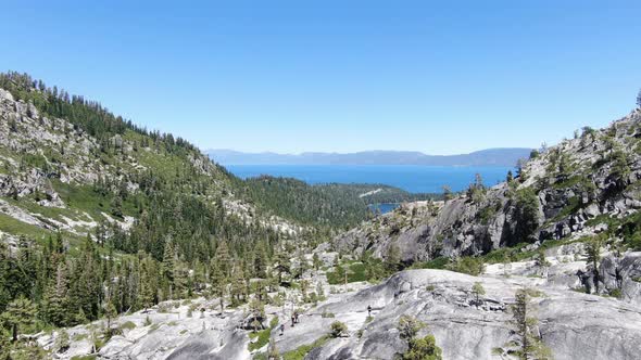 A slow pull away 4K drone aerial shot reveals Lake Tahoe in the background of a rocky canyon with a