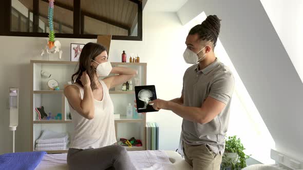 Physiotherapist discussing x-ray image of neck with female patient