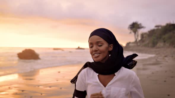 Somali-American woman jogging on the beach at sunset
