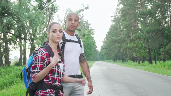 Beautiful Multiracial Couple Hitchhiking on Countryside Road