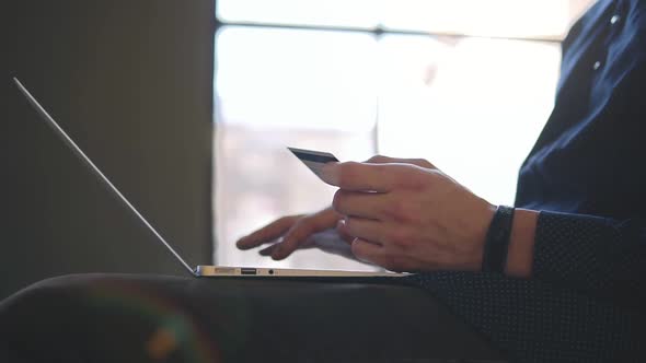 Male Hands Holding Credit Card and Typing Something on Laptop