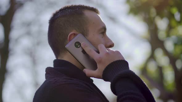 Young Man Having Conversation Through Modern Phone Outdoor