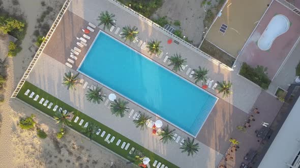 Top down aerial view of hotels on ocean shore with swimming pools with blue water and beach 