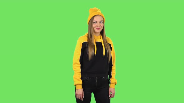 Modern Girl in Yellow Hat Is Coquettishly Smiling and Showing Gesture Come Here. Green Screen