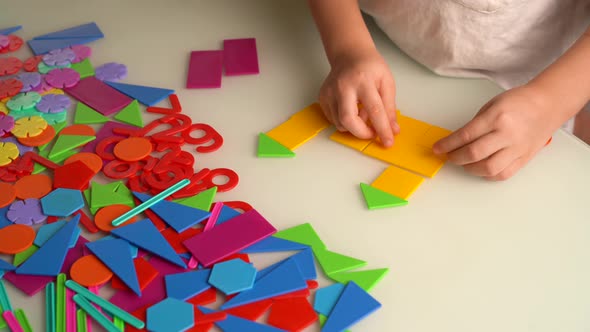 a Girl at a Round White Table Plays Educational Games a House Made of Designer Children's Hands