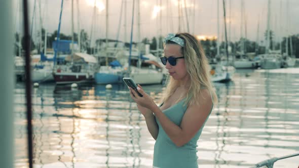 Gorgeous Lady Is Standing in the Harbour and Browsing Her Phone