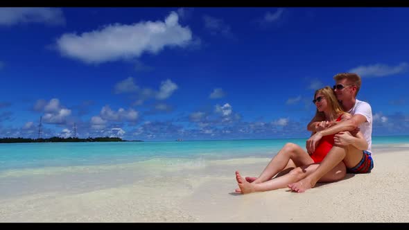 Boy and girl suntan on perfect bay beach break by blue green ocean with white sandy background of th