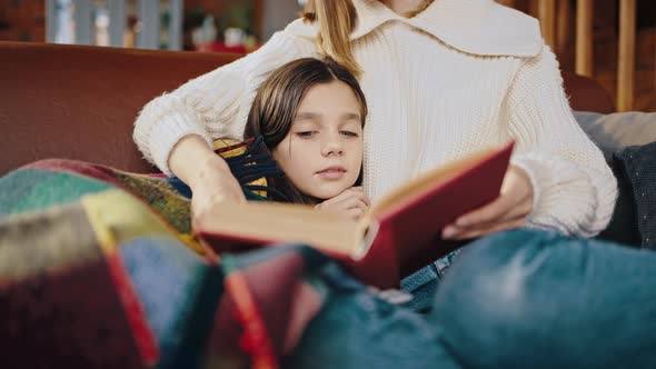 Unknown Mum Holding Book and Reading Fairy Tail to Preteen Daughter Who Following the Text with Eyes