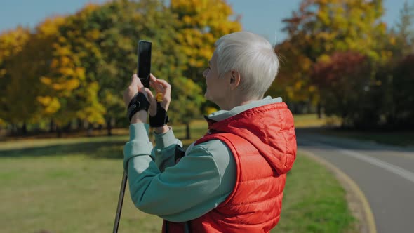 Woman Takes Video of Yellow Fall Park While Nordic Walking Wearing Sportswear