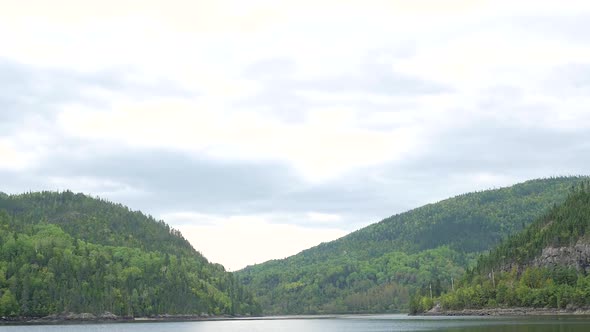 Cloudy Day Wide View Showing Lake With Mountains In The Background Covered In Trees