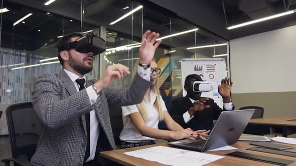 Two Serious Multiethnic Businessmen Wearing Virtual Reality Headset Making Joint Report 