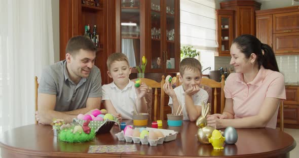 Happy Family Painting Easter Eggs in Kitchen