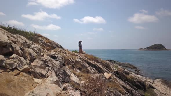 Aerial: a forward and close to the ground dolly in shot of a beautiful thai lady standing on a steep