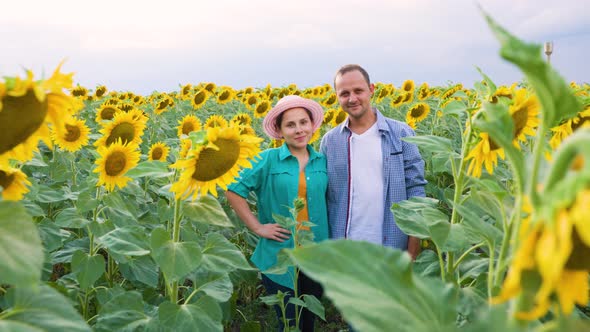 Front View of Happy Farmers Family in a Field with Sunflowers Looking at the Camera