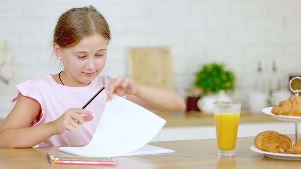 Girl Draws While Sitting in the Kitchen