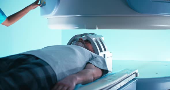 Crop Black Doctor Releasing Aged Man From MRI Machine