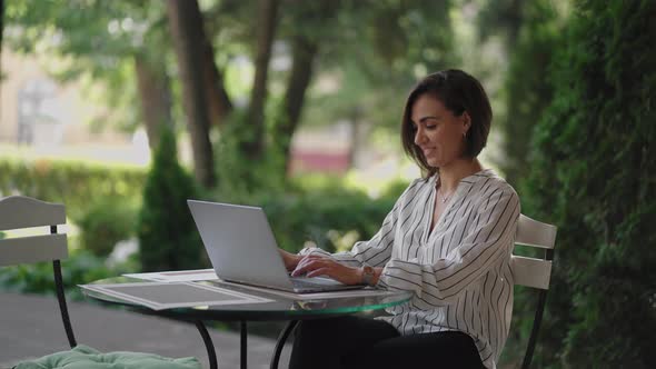 Business Woman Brunette Arabic Hispanic Ethnic Group is Typing on a Laptop While Sitting at a Table